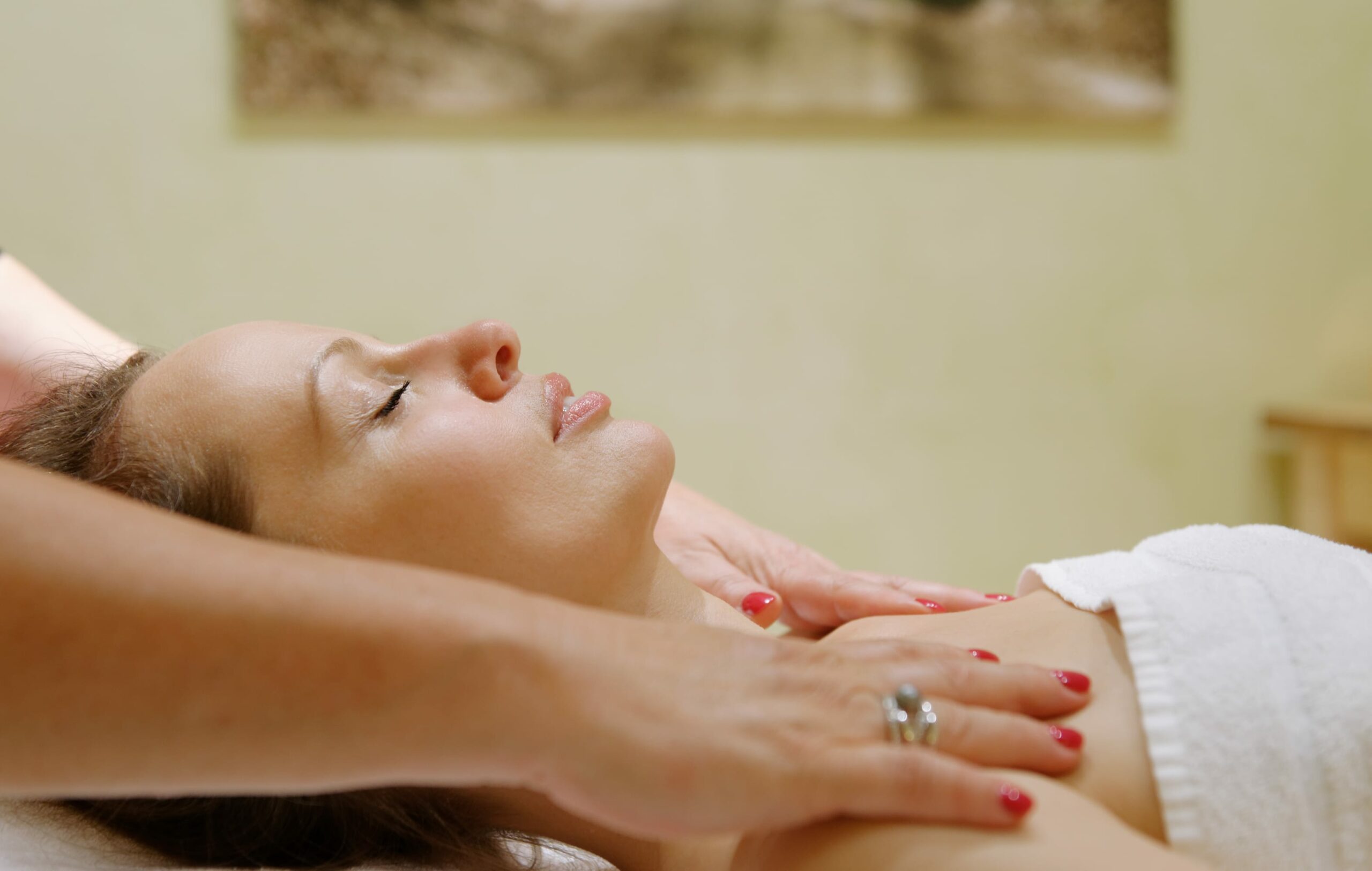 Frau liegt auf dem Rücken, Schultern werden massiert bei einer Massage im Spa Refugium im Wellness Hotel Sellhorn in der Lüneburger Heide